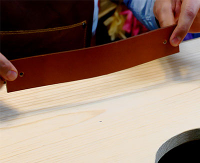 Fotografía del proceso de instalación de la jaladera de cuero en el cajón de madera